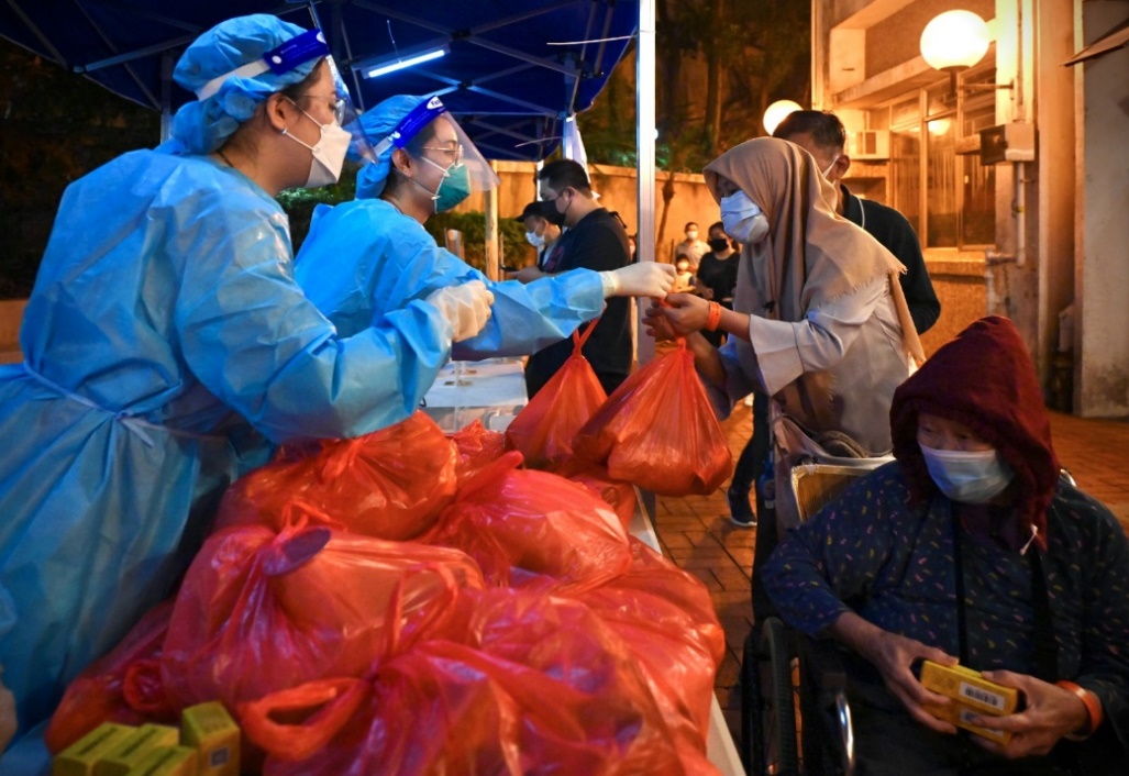 职员向受检人士派发食物包和由中央人民政府捐赠的抗疫中成药